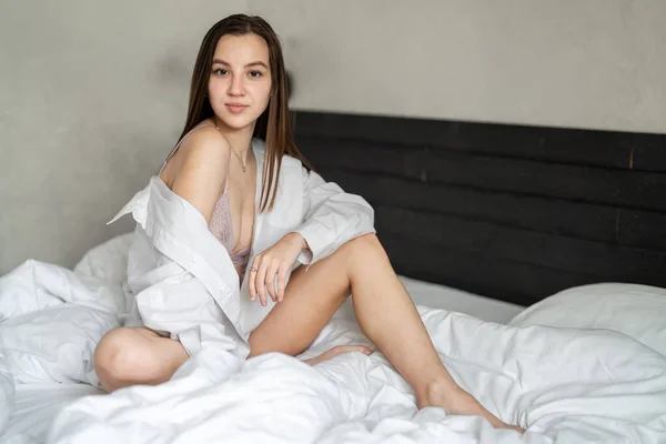 美丽的小女孩正坐在卧室的床上 穿着白衬衫 肖像画 — 图库照片