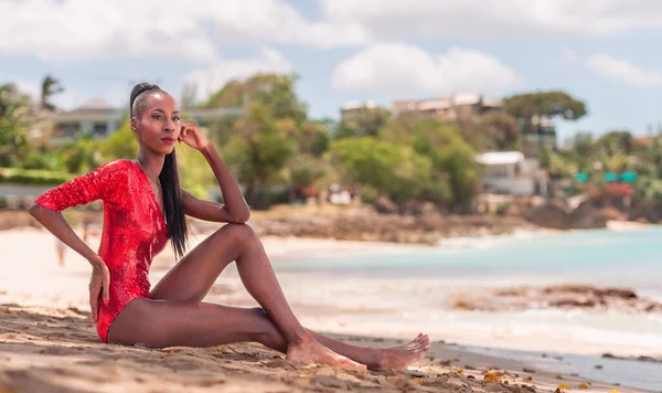 stock image Portrait of Beautiful Caribbean Adult Teen in Barbados. Wearing Red Bikini and Sitting on a tropical beach. Caribbean Sea in Background. Black. Portrait.