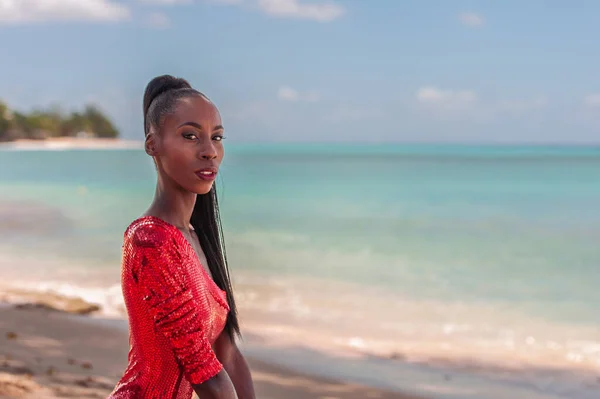 stock image Portrait of Beautiful Caribbean Adult Teen in Barbados. Wearing Red Bikini and Sitting on a tropical beach. Caribbean Sea in Background. Black. Portrait.