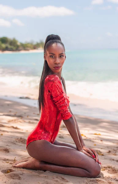 stock image Portrait of Beautiful Caribbean Adult Teen in Barbados. Wearing Red Bikini and Sitting on a tropical beach. Caribbean Sea in Background. Black. Portrait.