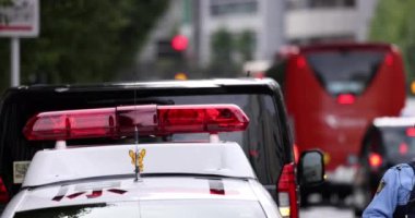 Tokyo, Japonya 'da trafik ihlalleri üzerine yürüyen bir polis memuru. Polis arabası ve yanıp sönen kırmızı ışık