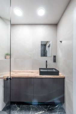 Modern mermer banyodaki lüks krom duşun içi. Geniş bir banyo, gri tonlarda ve ısıtmalı döşemeleri var. Mobilya, lavabo, duş. Mermer.