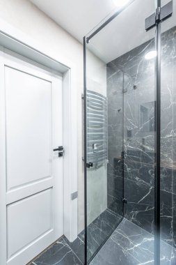 Modern mermer banyodaki lüks krom duşun içi. Geniş bir banyo, gri tonlarda ve ısıtmalı döşemeleri var. Mobilya, lavabo, duş. Mermer.