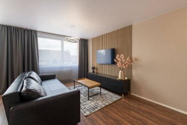 Modern Ev Oturma Odası İçi. Lüks modern apartman dairesi. Açık Alan, şık siyah deri kanepe, kahve masası, İskandinav tasarımı. Pencereler ve Perdeler. Yerde halı, TV ekranı.