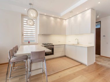 İskandinav tarzı rahat modern açık minimalizm mutfak iç mimarisi. Arka planda fırın, musluk ve mobilya var. Koyu Kahverengi Döşeme. Beyaz Dolaplar. Geniş Açı