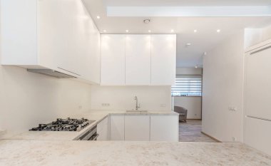 İskandinav tarzı rahat modern açık minimalizm mutfak iç mimarisi. Arka planda fırın, musluk ve mobilya var. Koyu Kahverengi Döşeme. Beyaz Dolaplar. Geniş Açı