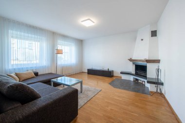 Modern Ev Oturma Odası İçi. Lüks modern apartman dairesi. Açık Alan, Şık Koltuk, Kahve Masası, İskandinav Tasarımı. Pencereler ve Perdeler. Yerde halı var. Şömine