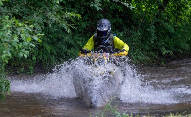 Moto ekipmanlı profesyonel motosikletçi doğada dayanıklı bisiklet sürüyor, sürücü çamurda ve su birikintilerinde sürüyor, motosiklet yarışı yapıyor. Off-road turnuvası. Ormanda dayanıklı sporlarda motosikletliler