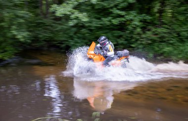 Moto ekipmanlı profesyonel motosikletçi doğada dayanıklı bisiklet sürüyor, sürücü çamurda ve su birikintilerinde sürüyor, motosiklet yarışı yapıyor. Off-road turnuvası. Ormanda dayanıklı sporlarda motosikletliler