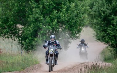 Moto ekipmanlı profesyonel bir motosikletçi. Doğada dayanıklı bisiklet sürüyor. Sürücü çakıllı yolda, motosiklet yarışında. Off-road turnuvası. Ormanda dayanıklı sporlarda motosikletliler