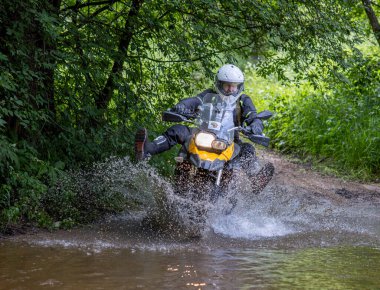 Moto ekipmanlı profesyonel motosikletçi doğada dayanıklı bisiklet sürüyor, sürücü çamurda ve su birikintilerinde sürüyor, motosiklet yarışı yapıyor. Off-road turnuvası. Ormanda dayanıklı sporlarda motosikletliler