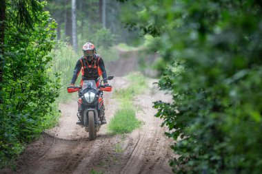 Moto ekipmanlı profesyonel bir motosikletçi. Doğada dayanıklı bisiklet sürüyor. Sürücü çakıllı yolda, motosiklet yarışında. Off-road turnuvası. Ormanda dayanıklı sporlarda motosikletliler