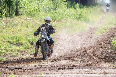 Moto ekipmanlı profesyonel bir motosikletçi. Doğada dayanıklı bisiklet sürüyor. Sürücü çakıllı yolda, motosiklet yarışında. Off-road turnuvası. Ormanda dayanıklı sporlarda motosikletliler
