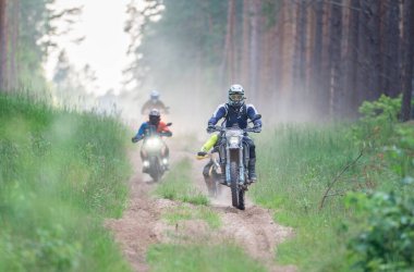 Moto ekipmanlı profesyonel bir motosikletçi. Doğada dayanıklı bisiklet sürüyor. Sürücü çakıllı yolda, motosiklet yarışında. Off-road turnuvası. Ormanda dayanıklı sporlarda motosikletliler
