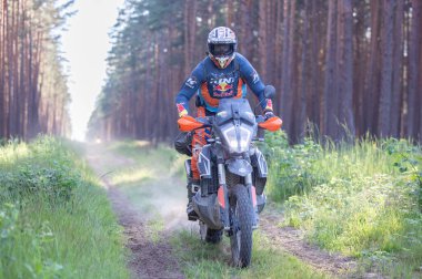 Moto ekipmanlı profesyonel bir motosikletçi. Doğada dayanıklı bisiklet sürüyor. Sürücü çakıllı yolda, motosiklet yarışında. Off-road turnuvası. Ormanda dayanıklı sporlarda motosikletliler