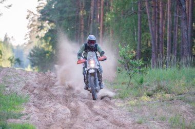Moto ekipmanlı profesyonel bir motosikletçi. Doğada dayanıklı bisiklet sürüyor. Sürücü çakıllı yolda, motosiklet yarışında. Off-road turnuvası. Ormanda dayanıklı sporlarda motosikletliler