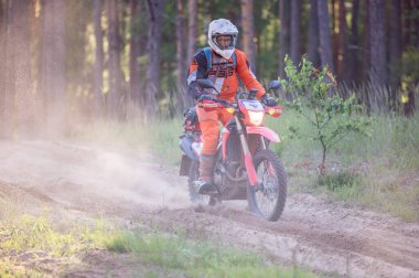 Moto ekipmanlı profesyonel bir motosikletçi. Doğada dayanıklı bisiklet sürüyor. Sürücü çakıllı yolda, motosiklet yarışında. Off-road turnuvası. Ormanda dayanıklı sporlarda motosikletliler