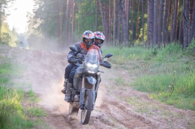 Moto ekipmanlı profesyonel bir motosikletçi. Doğada dayanıklı bisiklet sürüyor. Sürücü çakıllı yolda, motosiklet yarışında. Off-road turnuvası. Ormanda dayanıklı sporlarda motosikletliler