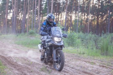 Moto ekipmanlı profesyonel bir motosikletçi. Doğada dayanıklı bisiklet sürüyor. Sürücü çakıllı yolda, motosiklet yarışında. Off-road turnuvası. Ormanda dayanıklı sporlarda motosikletliler