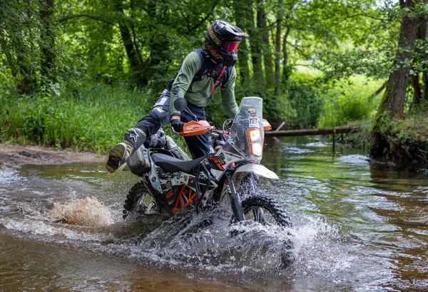 Moto ekipmanlı profesyonel motosikletçi doğada dayanıklı bisiklet sürüyor, sürücü çamurda ve su birikintilerinde sürüyor, motosiklet yarışı yapıyor. Off-road turnuvası. Ormanda dayanıklı sporlarda motosikletliler