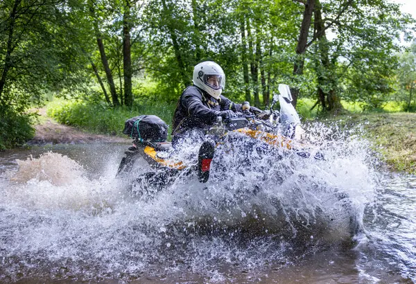 Moto ekipmanlı profesyonel motosikletçi doğada dayanıklı bisiklet sürüyor, sürücü çamurda ve su birikintilerinde sürüyor, motosiklet yarışı yapıyor. Off-road turnuvası. Ormanda dayanıklı sporlarda motosikletliler