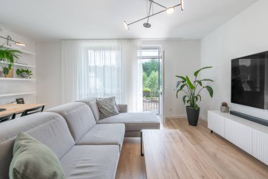 Modern Ev Oturma Odası İçi. Lüks modern apartman dairesi. Açık iç mekan, stil koltuğu, kahve masası, İskandinav tasarımı. TV Ekranı, Pencereler ve Perdeler.