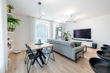 Modern Ev Oturma Odası İçi. Lüks modern apartman dairesi. Açık iç mekan, stil koltuğu, kahve masası, İskandinav tasarımı. TV Ekranı, Pencereler ve Perdeler.