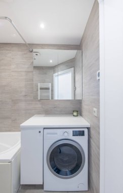 Parlak Zarif Modern Minimalist Banyo Duş Odasının İç Tasarımı. Banyo aksesuarları, gri fayans duvarları, ayna, çamaşırhane. LED Işık.