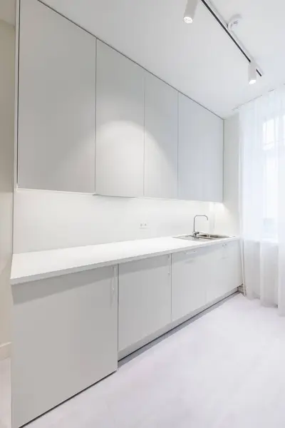 İskandinav tarzı rahat modern açık minimalizm mutfak iç mimarisi. Arka planda fırın, musluk ve mobilya var. Koyu Kahverengi Döşeme. Beyaz Dolaplar. Geniş Açı