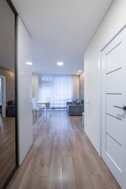 İskandinav Tarzı Konforlu Modern Açık Parlak Mutfak İç Bölgesi. Yemek masası, ahşap döşeme, pencereler ve perdeler. Arka plandaki kanepe. Entrace Hall, Koridor, Koridor. Geniş Açı