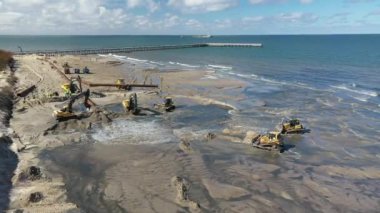 Plaj restorasyonu ve buldozerler. Denizin götürdüğü sahilin yeniden inşası için kazıcıyla birlikte borudan çamur akıyor. Plaj besinleri için çalışmalar devam ediyor. Drone Hava Çekimi