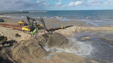 Plaj restorasyonu ve buldozerler. Denizin götürdüğü sahilin yeniden inşası için kazıcıyla birlikte borudan çamur akıyor. Plaj besinleri için çalışmalar devam ediyor. Drone Hava Çekimi