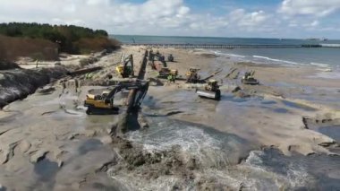 Plaj restorasyonu ve buldozerler. Denizin götürdüğü sahilin yeniden inşası için kazıcıyla birlikte borudan çamur akıyor. Plaj besinleri için çalışmalar devam ediyor. Drone Hava Çekimi