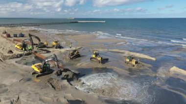 Plaj restorasyonu ve buldozerler. Denizin götürdüğü sahilin yeniden inşası için kazıcıyla birlikte borudan çamur akıyor. Plaj besinleri için çalışmalar devam ediyor. Drone Hava Çekimi