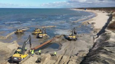 Plaj restorasyonu ve buldozerler. Denizin götürdüğü sahilin yeniden inşası için kazıcıyla birlikte borudan çamur akıyor. Plaj besinleri için çalışmalar devam ediyor. Drone Hava Çekimi