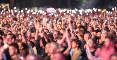 Birçok insan cep telefonu flaş ışığını kaldırır. Hayran kitlesi el sallıyor. Epic Live Music Concert Atmosfer. Büyük Açık Hava Arenası. Litvanya, Vilnius Şehri