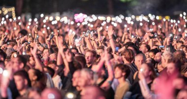 Birçok insan cep telefonu flaş ışığını kaldırır. Hayran kitlesi el sallıyor. Epic Live Music Concert Atmosfer. Büyük Açık Hava Arenası. Litvanya, Vilnius Şehri