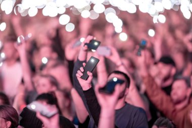 Birçok insan cep telefonu flaş ışığını kaldırır. Hayran kitlesi el sallıyor. Epic Live Music Concert Atmosfer. Büyük Açık Hava Arenası. Litvanya, Vilnius Şehri