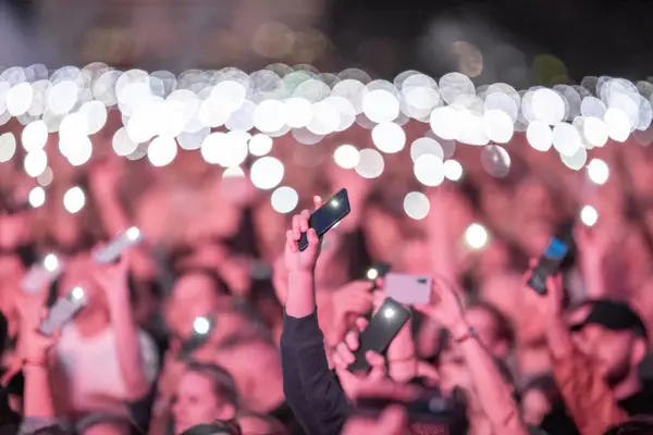 stock image Many People Lift Hand up Hold cell Phone Flash Light. Fan Crowd Wave Flashlights. Epic Live Music Concert Atmosphere. Big Open Air Arena. Lithuania, Vilnius City