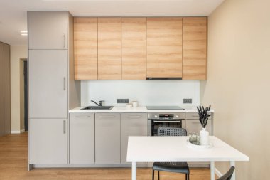 İskandinav tarzı rahat modern açık minimalizm mutfak iç mimarisi. Arka planda fırın, musluk, buzdolabı ve mobilya. Masada çiçekler var. Dolaplar. Geniş Açı