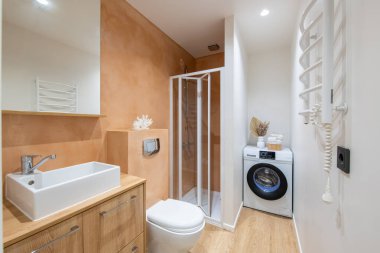 Beyaz Lavabolu Parlak Modern Lüks Banyo İç Tasarımı. Pembe Renkli Duvarlar, Ayna ve Musluk. LED ışıkları. Çamaşır makinesi. Duş kabini, ısıtıcı. Geniş Açı