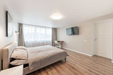 Lüks yatak odası, iç mekan, modern ev, güzel iç mekan, geniş yatak odası. Duvardaki TV seti. Büyük boy yatak, beyaz duvarlar ve tavan. Ahşap zemin. Geniş Açı