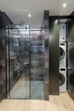 Karanlık Zarif Modern Lüks Banyo Duşun İç Tasarımı. LED ışıkları. Siyah Isıtıcı. Cam Duvar ve Duş Odası. LED Işık. Laudry ve Dryer için dolap kapısını açın. Geniş Açı
