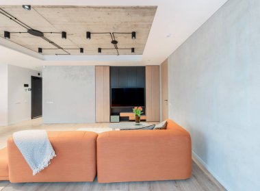 Modern Ev Oturma Odası. Lüks modern apartman dairesi. Açık iç mekan, portakal renkli kanepe, kanepe, gardırop, mobilya, İskandinav tasarımı. Masada çiçekler var. Pencere Perdeleri Halısı