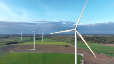 Rüzgar türbinlerinin hava görüntüleri zarifçe dönüyor ve daha fazla rüzgar türbini bulunuyor. Kıyıdaki ve tarımdaki sürdürülebilir sinerji. Güzel bir manzara. Altın Saat. 4k