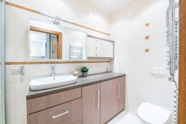 Beyaz Lavabolu Parlak Modern Lüks Banyo İç Tasarımı. Gri Duvarlar, Ayna ve Musluk, Gümüş Kalorifer. LED ışıkları. Geniş Açı
