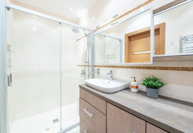 Beyaz Lavabolu Parlak Modern Lüks Banyo İç Tasarımı. Gri Duvarlar, Ayna ve Musluk. LED ışıkları. Tahta Kapı. Geniş Açı