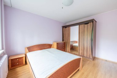 Minimalizm yatak odası iç mimarisi. Arka plandaki gardırop ve pencere. Daire kiraya hazır. Beyaz ısıtıcı. Eski Sovyet tarzı iç mekan. İç mekan. Pembe Duvarlar. Gardırop ve Ayna. Ev