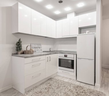 Modern Minimalist Home Kitchen Interior with White Cabinets and Warm Decorative Elements. Bright clean modern kitchen featuring white cabinetry cozy decorations comfortable atmosphere for daily use.