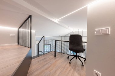 Modern ergonomik bir sandalye, büyük ahşap döşeme ve parlak minimalist tasarım elementleri içeren şık ofis odası, fonksiyonel çalışma ortamı arayan yaratıcı profesyoneller için mükemmel..